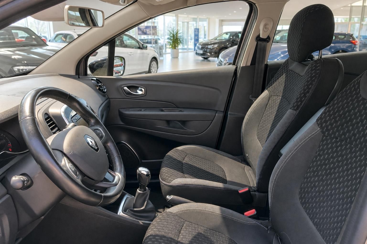 Renault Innenraum Fahrersitz mit Lenkrad, Schalthebel und schwarzen Stoffsitzen im Autohaus