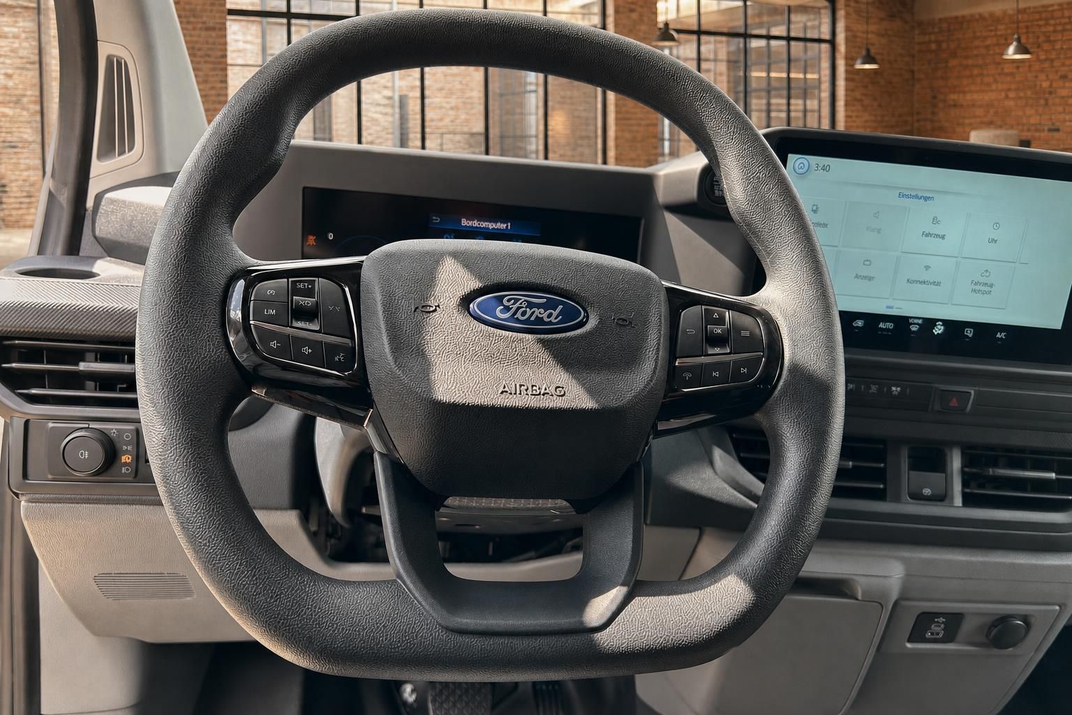 Ford Transit Lenkrad mit Multifunktionstasten, Airbag und Infotainment-Display im Hintergrund