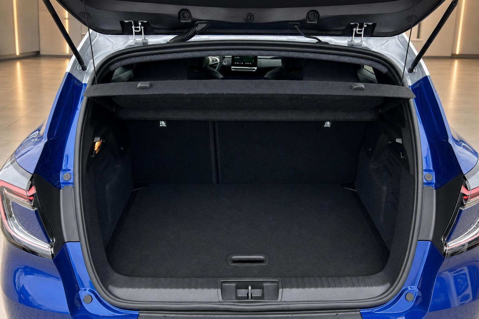 Kofferraum eines blauen Fahrzeugs mit geöffneter Heckklappe und schwarzer Innenausstattung