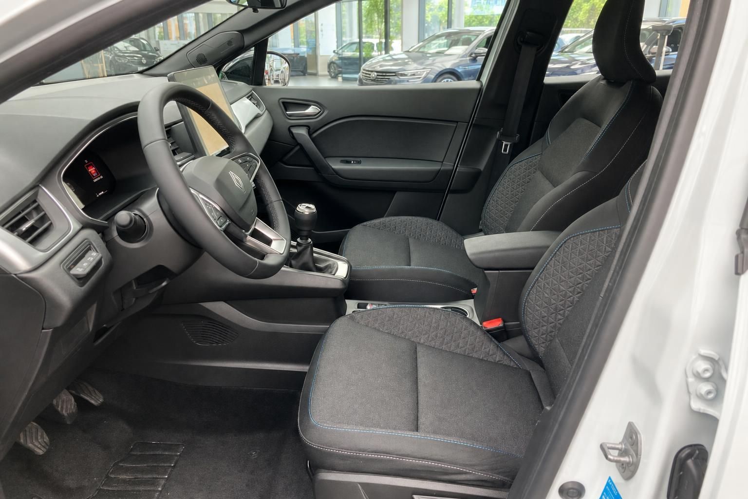 Renault Clio Innenraum Fahrersitz mit Lenkrad, Schaltgetriebe und schwarzen Stoffsitzen mit blauer Ziernaht