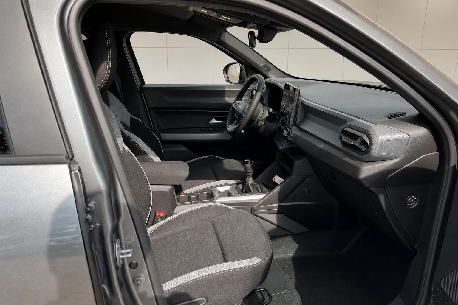 Blick durch offene Fahrertür auf Cockpit und Vordersitze des Fahrzeugs