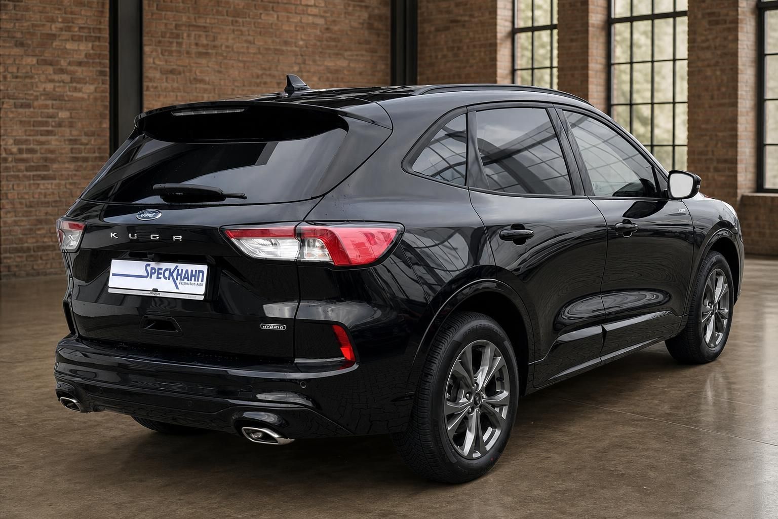 Ford Kuga Hybrid schwarz Heck seitlich vor Backsteinwand im Autohaus