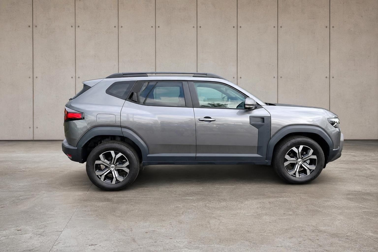 Dacia Duster grau SUV Seitenansicht vor Betonwand