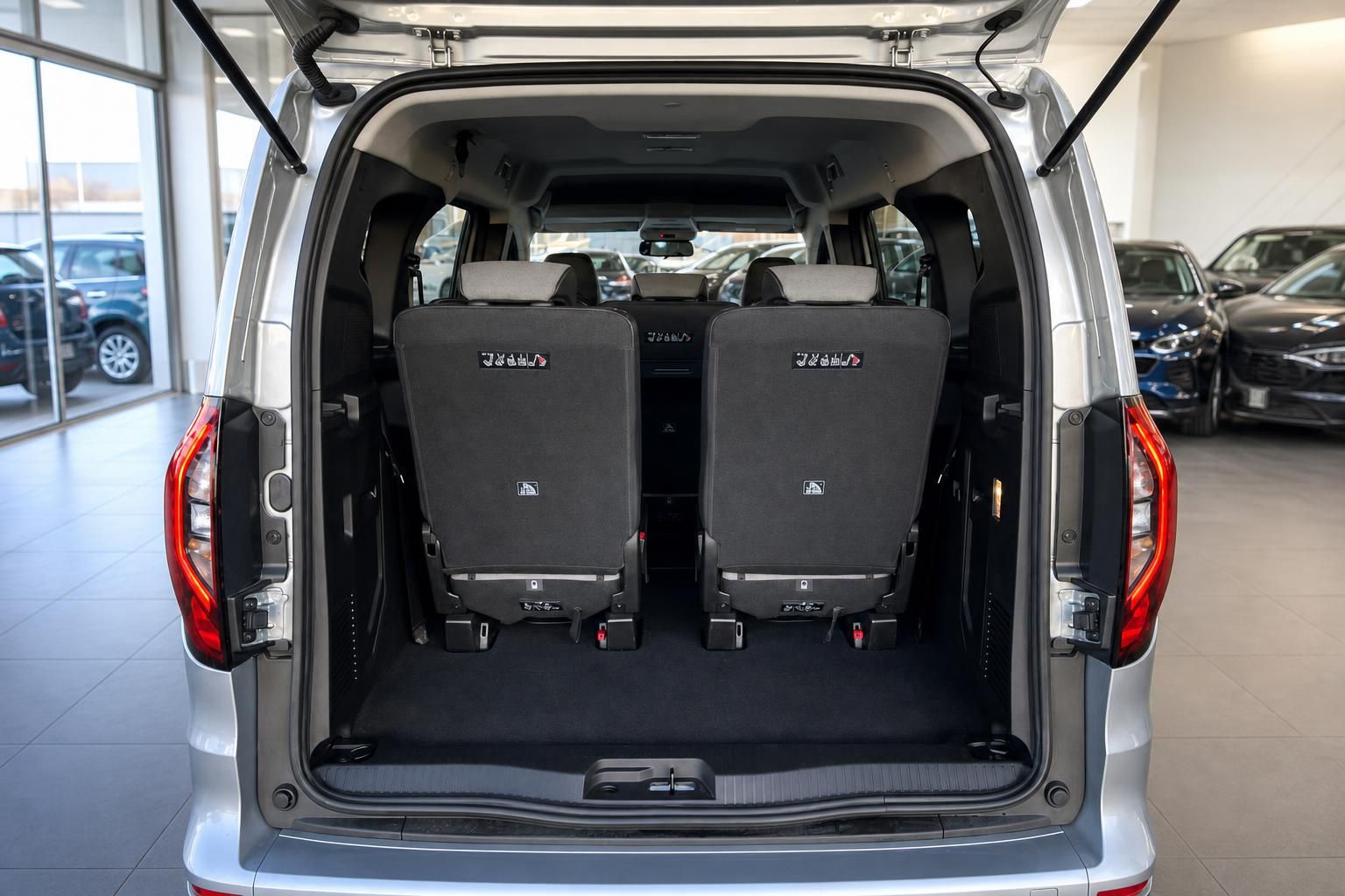 Kofferraum eines silbernen Transporters mit umgeklappten Rücksitzen und geöffneter Heckklappe
