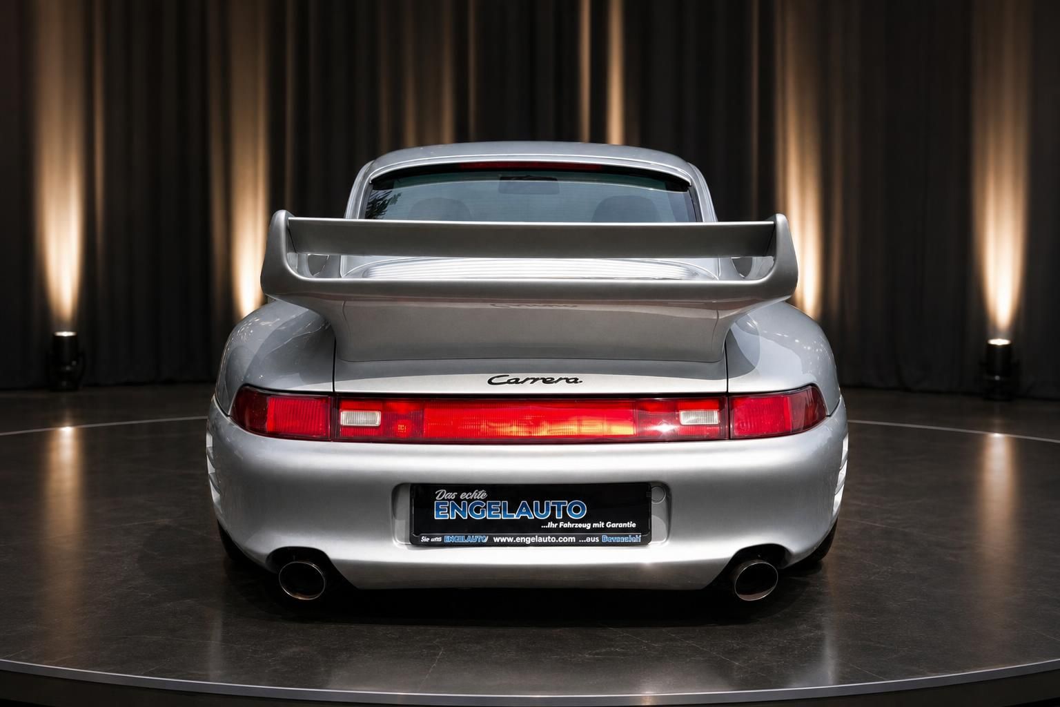 Porsche 911 Carrera silber metallic Heckansicht mit Spoiler in moderner Ausstellungshalle