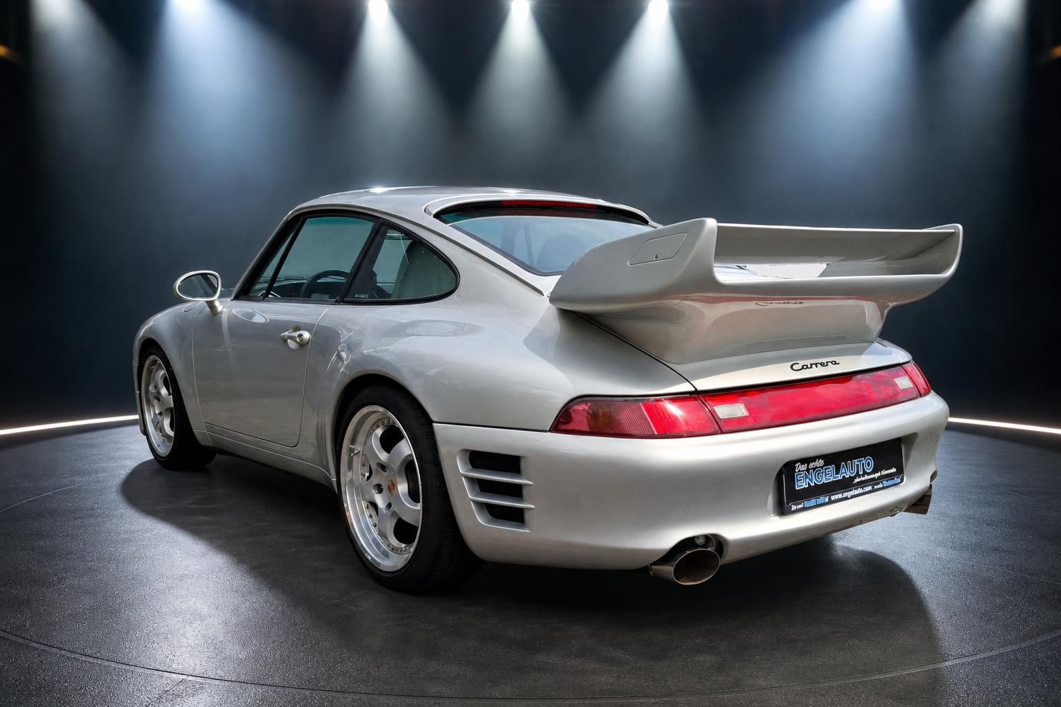 Porsche 911 Carrera silber schräg hinten mit großem Heckspoiler und Sportfelgen