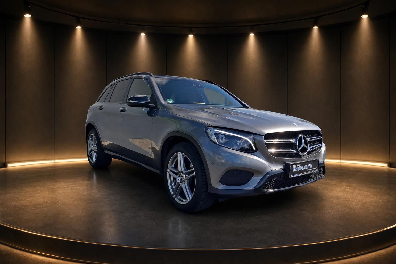 Mercedes GLC SUV in silbergrau, Dreiviertelansicht vorne links im Showroom mit LED-Beleuchtung