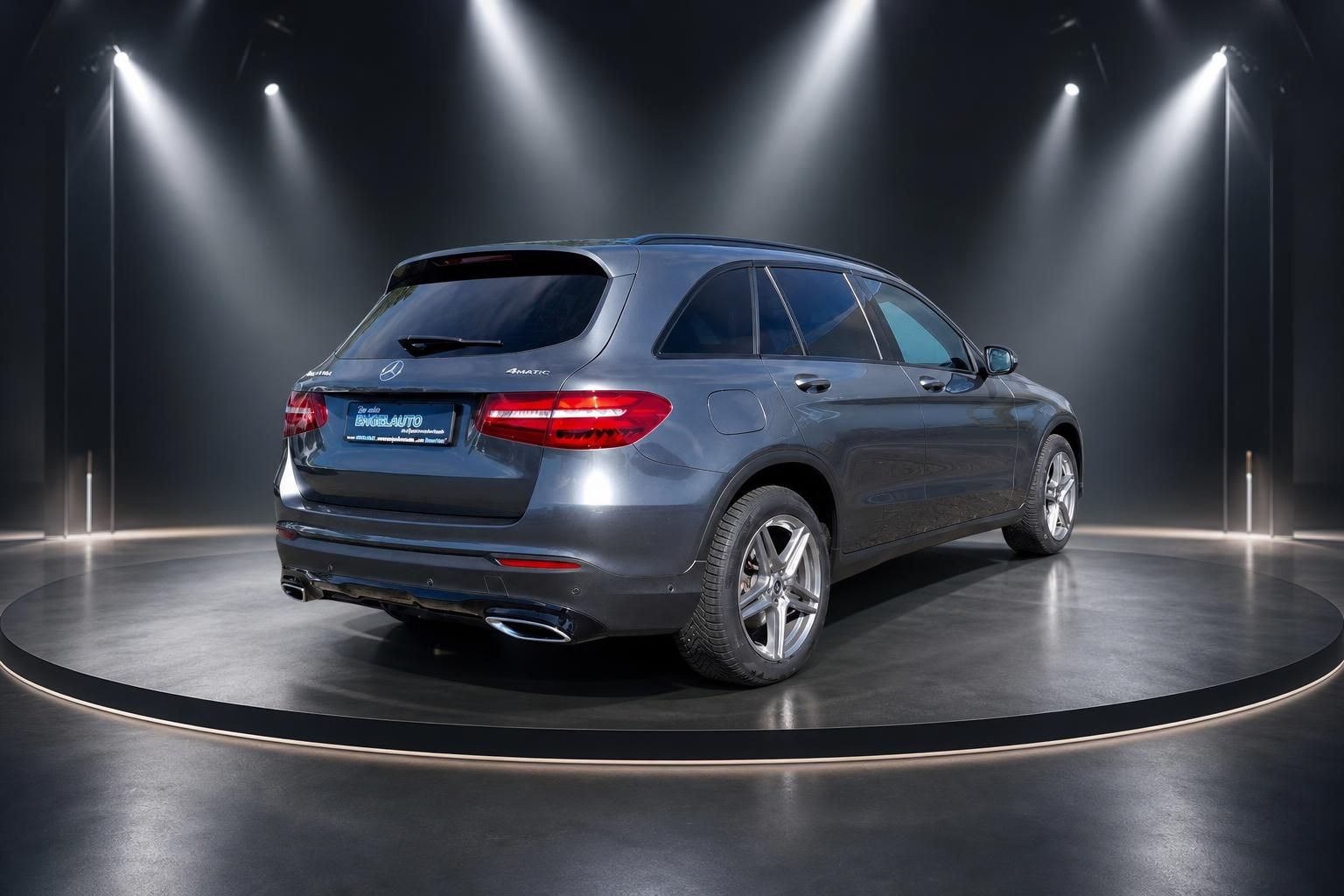 Mercedes GLC SUV in silbergrau, Heckansicht schräg hinten rechts im beleuchteten Showroom