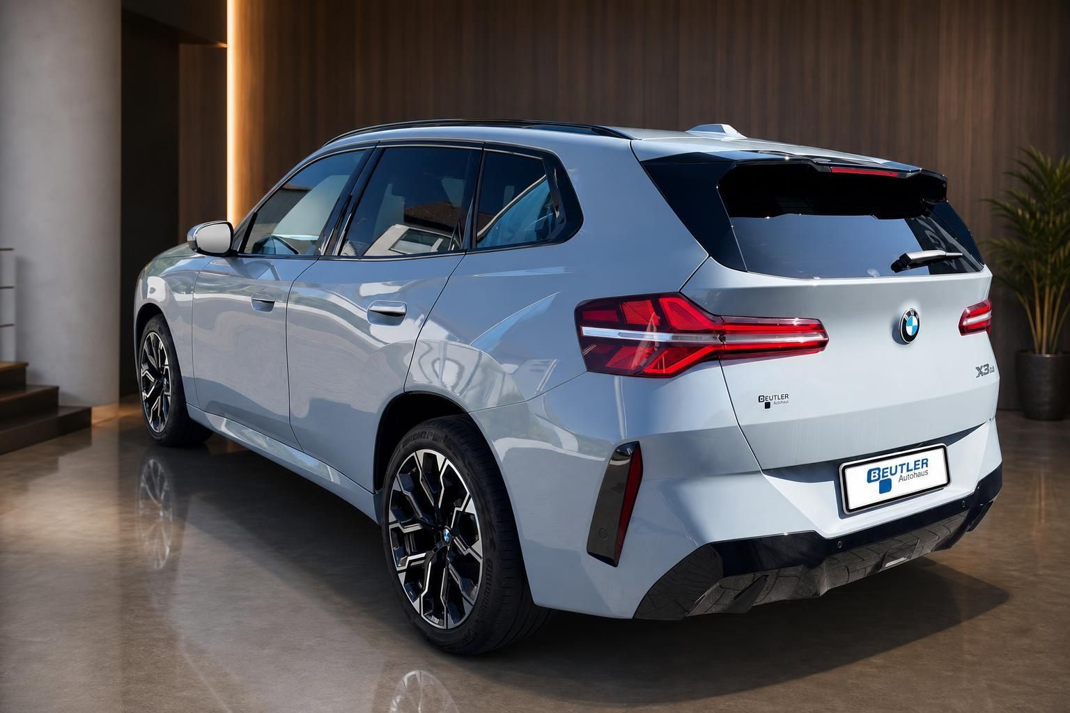 BMW X3 hellblau, Heckansicht schräg in edlem Showroom