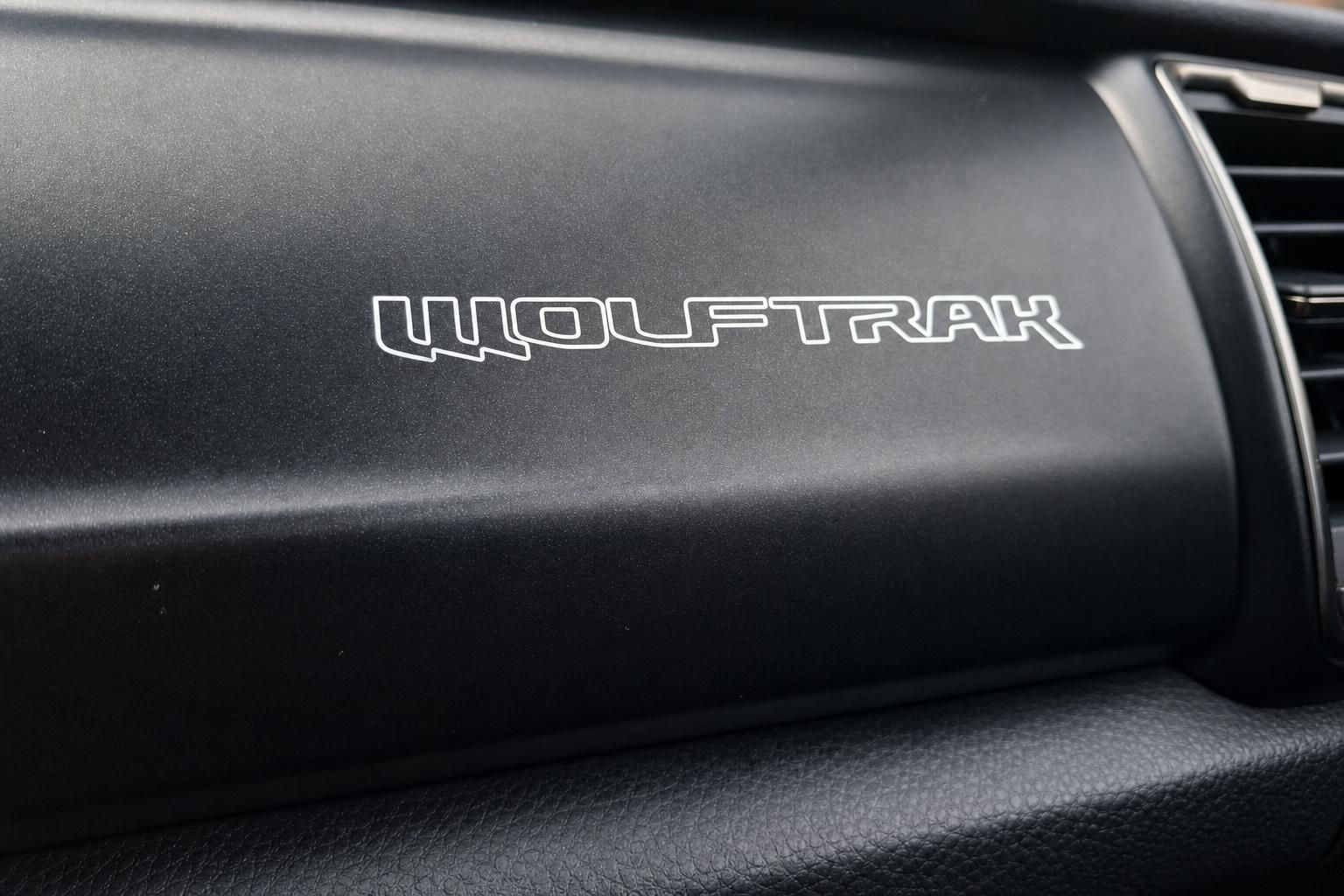 WOLFTRAK Schriftzug auf schwarzem Fahrzeug-Armaturenbrett mit Lüftungsschlitz im Detail
