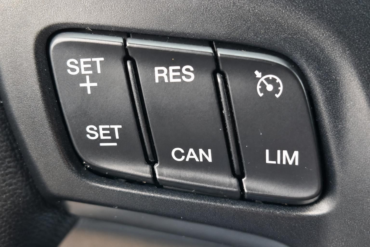Tempomat-Bedienelemente SET RES CAN LIM im schwarzen Fahrzeug-Cockpit Detail