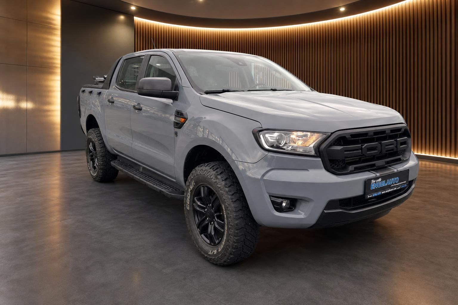 Ford Ranger Pickup silber Schrägansicht vorne rechts mit schwarzen Felgen und Holzwand-Hintergrund