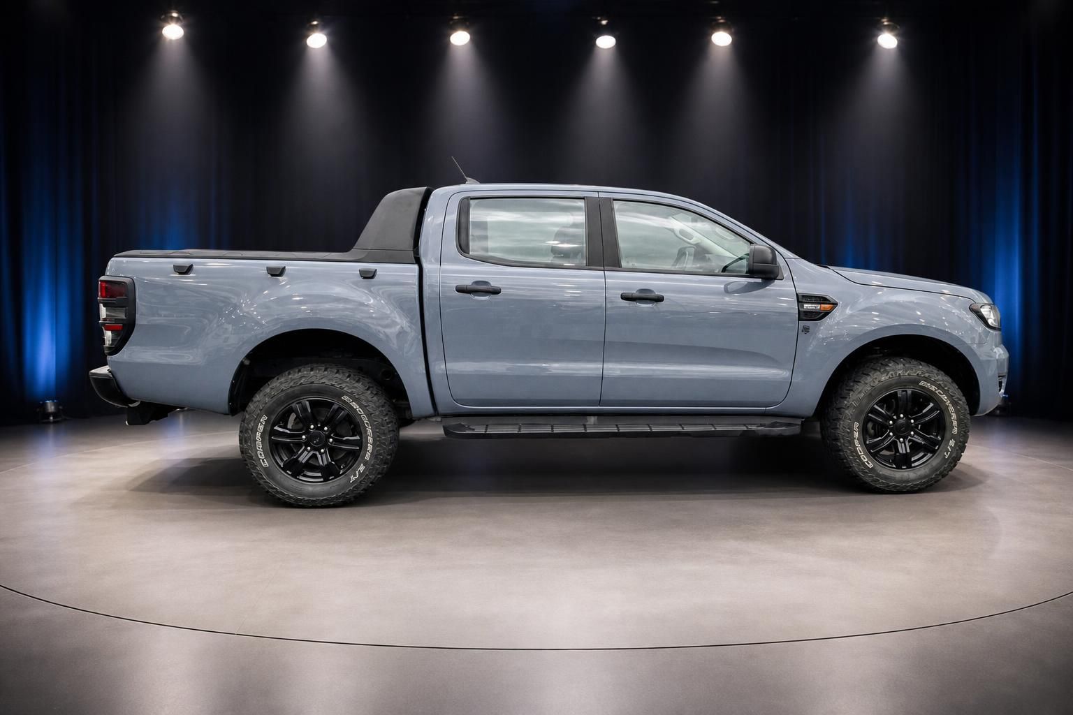 Ford Ranger Pickup silber Seitenansicht mit schwarzen Felgen und Geländereifen im Showroom