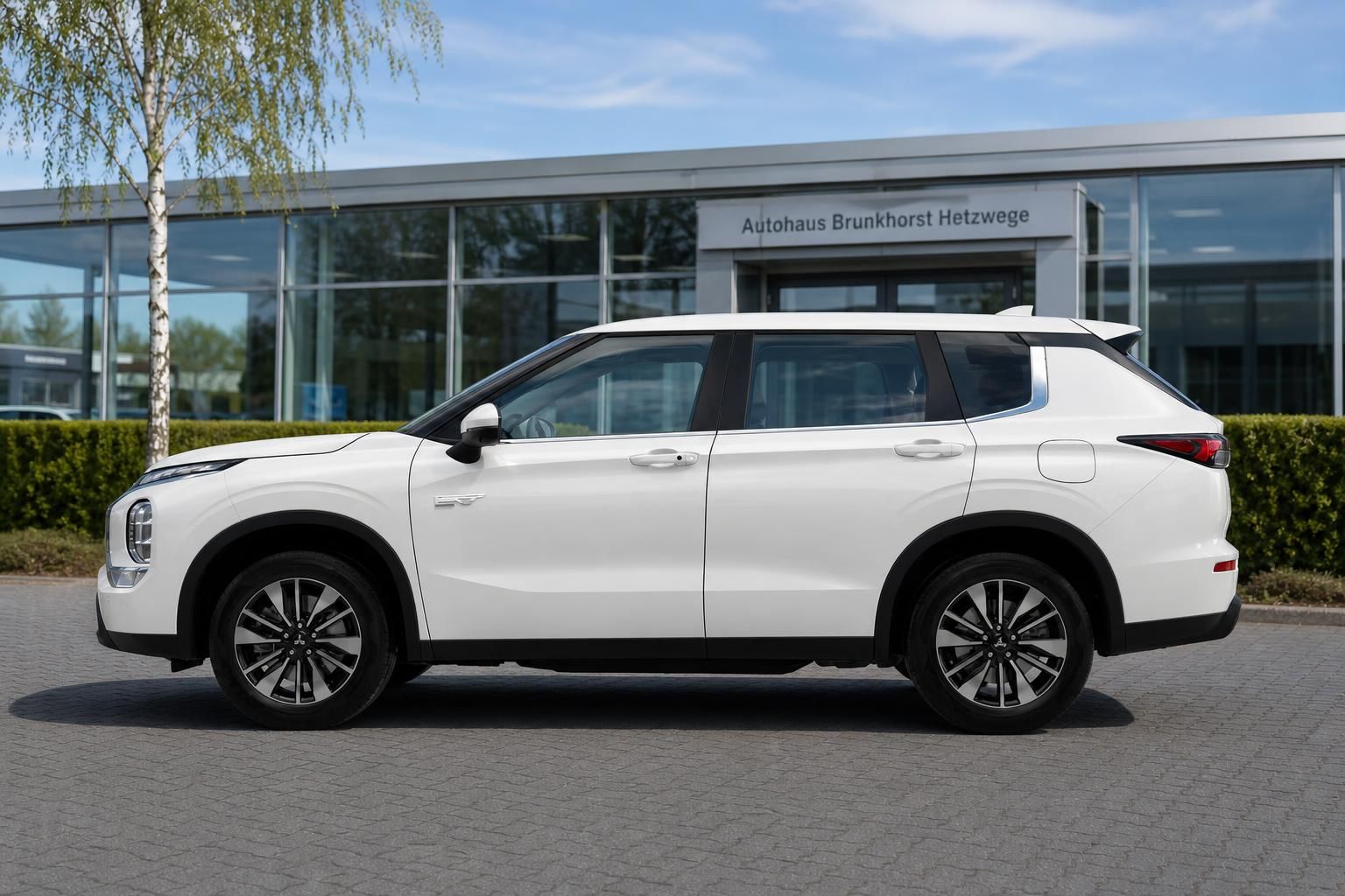Weißer Mitsubishi Outlander SUV Seitenansicht vor Autohaus Brunkhorst Hetzwege