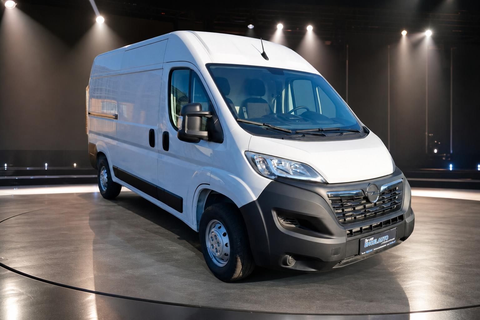 Weißer Transporter Kastenwagen im Showroom - Frontansicht drei Viertel mit LED-Beleuchtung