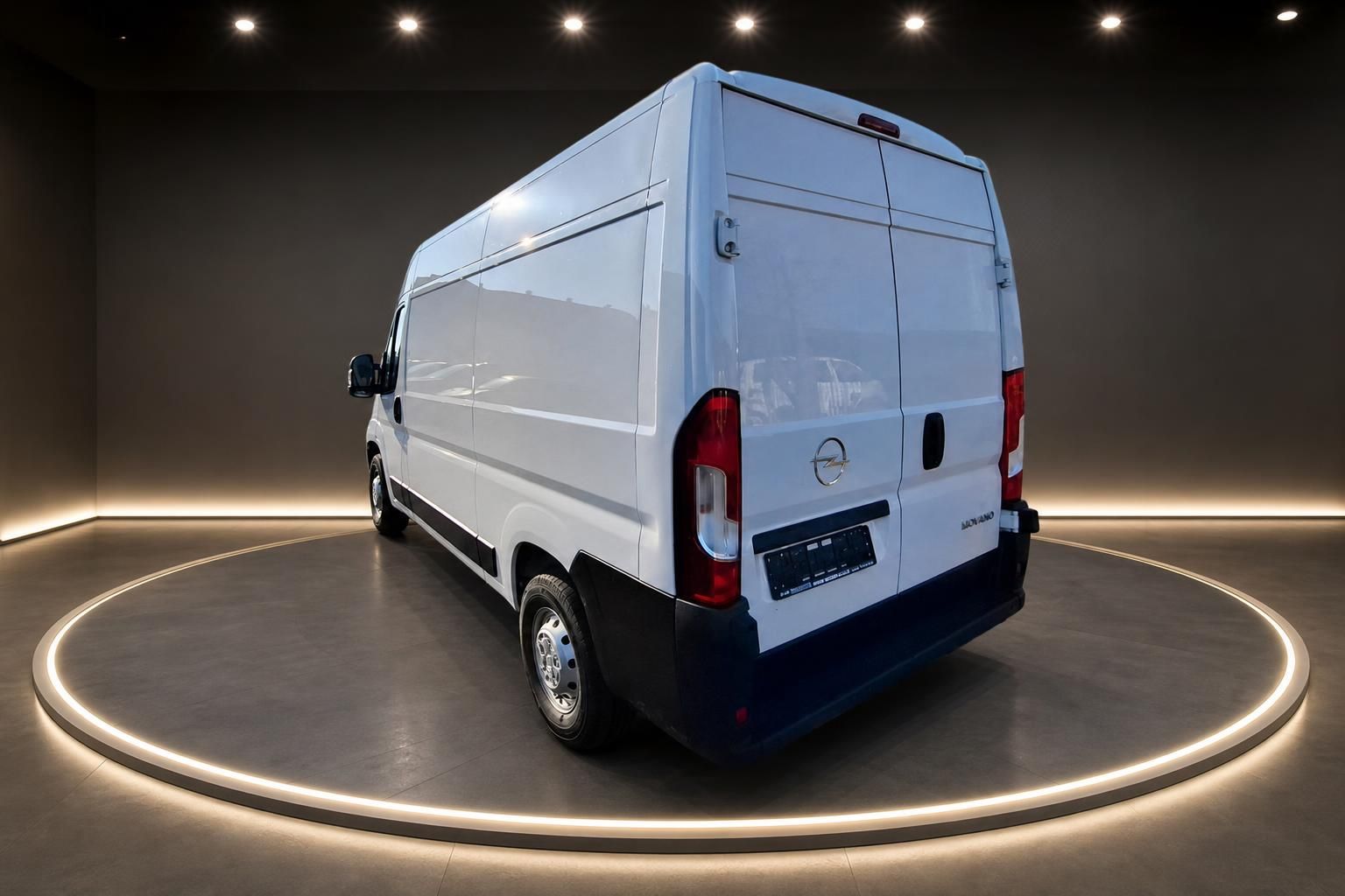 Weißer Opel Transporter auf drehbarem Podest im Showroom - Seitenansicht von hinten rechts