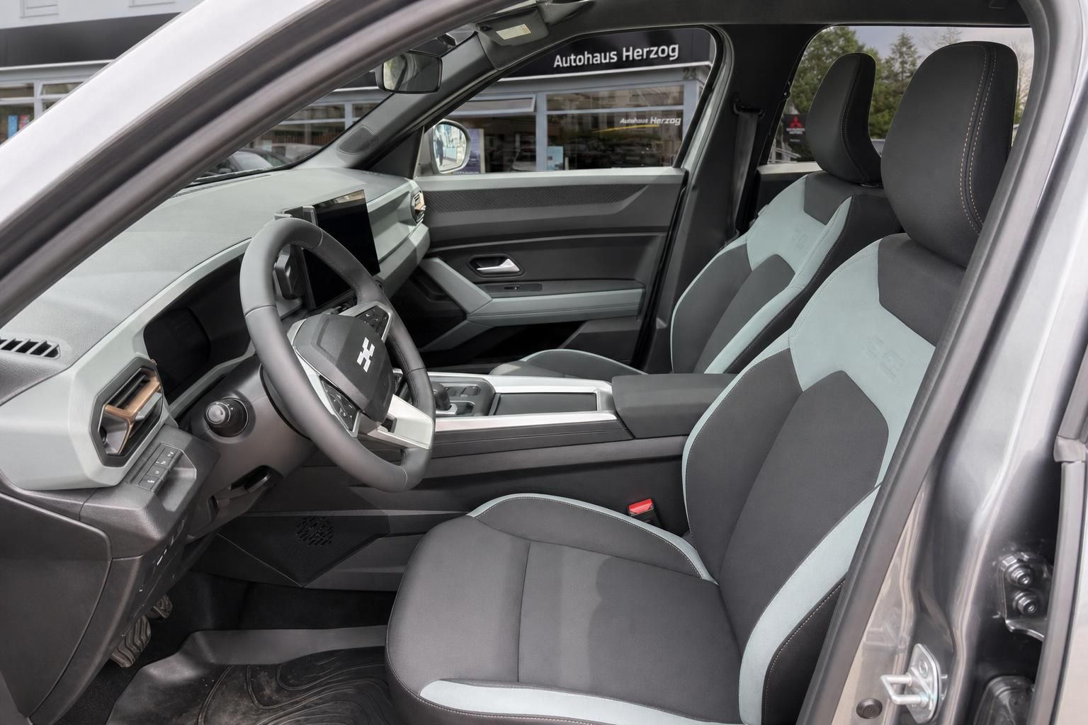 Fahrzeug Innenraum mit grau-weißen Sitzen und modernem Cockpit - Fahrerperspektive