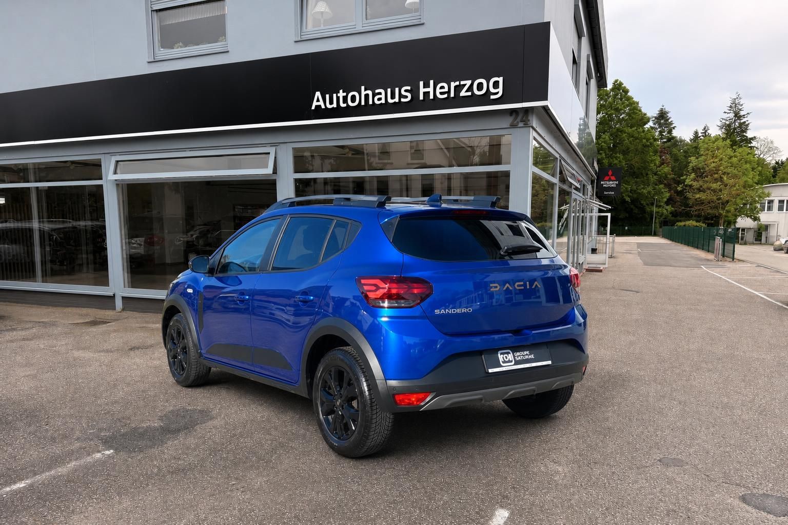 Blauer Dacia Sandero Crossover von hinten vor Autohaus Herzog Showroom