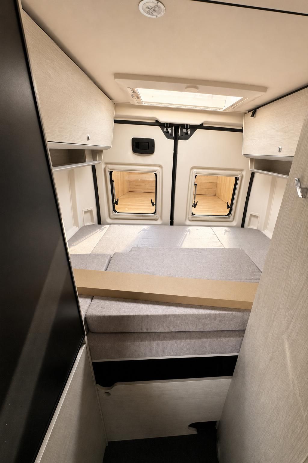 Schlafbereich im Camper mit Fenstern und Stauraum