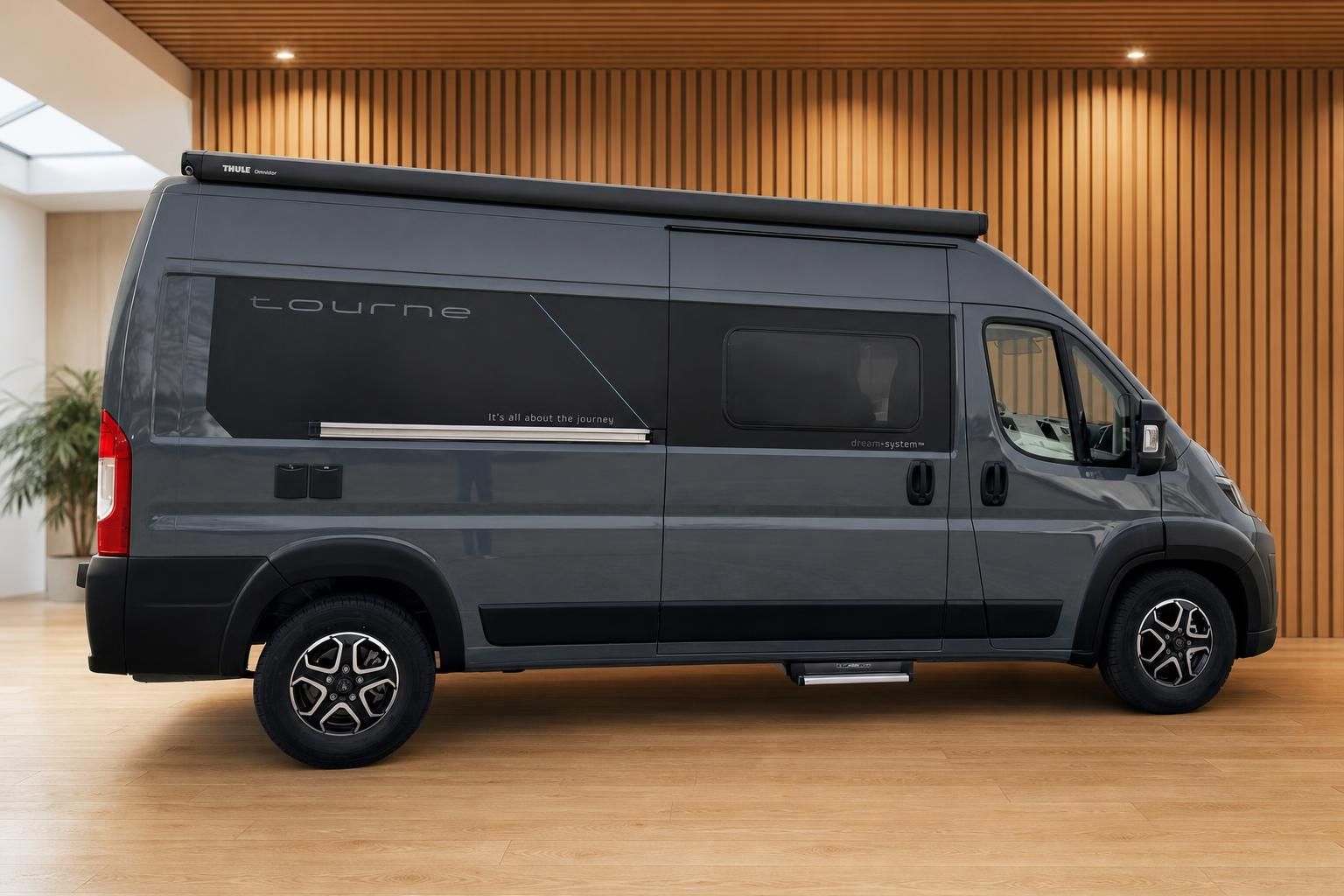 Dunkelgrauer Tourne Camperbus Seitenansicht mit Thule Markise im Showroom