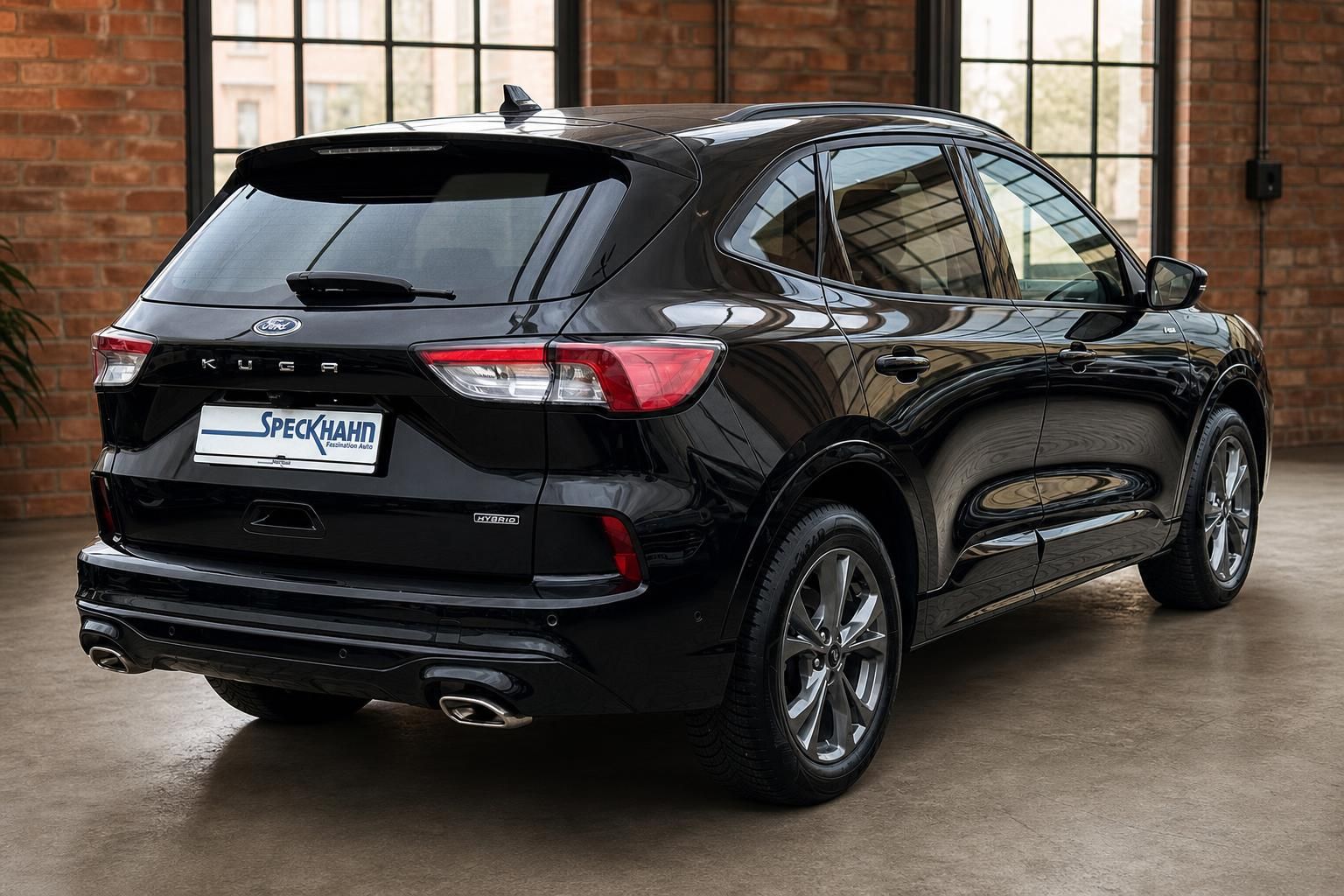 Ford Kuga Hybrid schwarz Heckansicht schräg in Ausstellungshalle