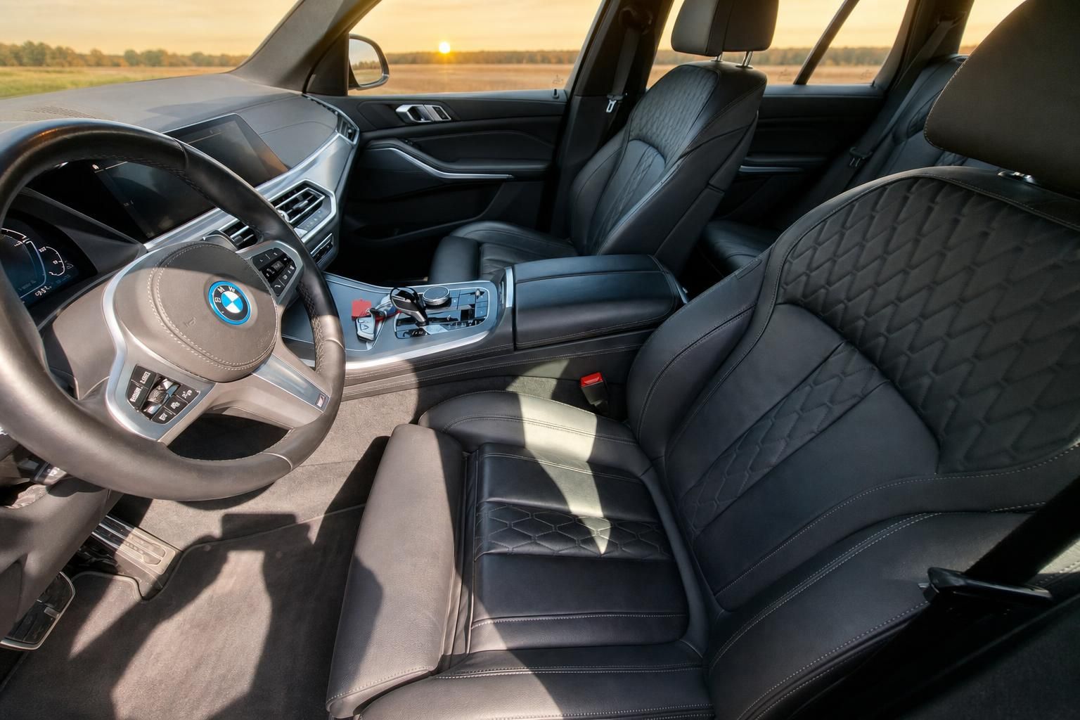 BMW Innenraum mit schwarzen Ledersitzen und Lenkrad bei Sonnenuntergang