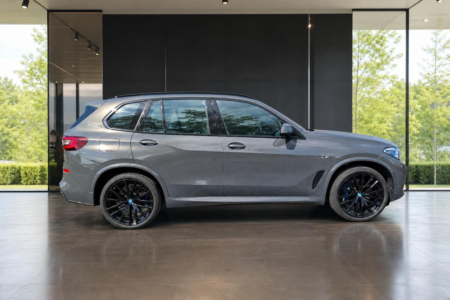BMW X5 grau, Seitenansicht mit schwarzen Felgen im Showroom