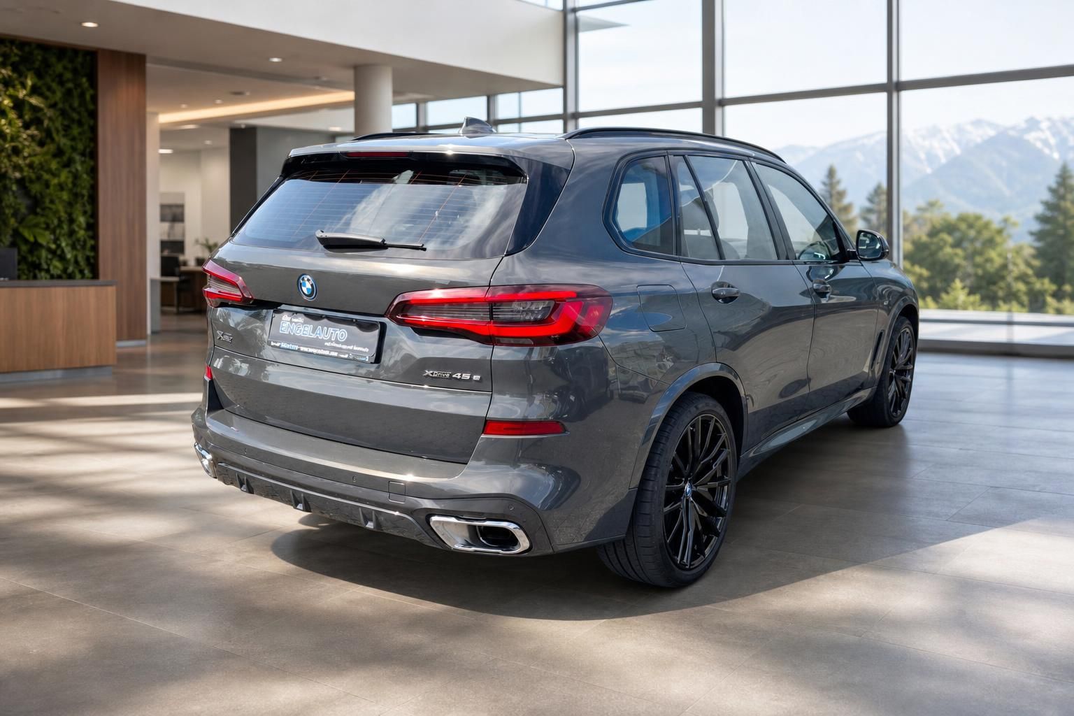 BMW X5 xDrive45e grau, Heckansicht im Autohaus mit Bergpanorama