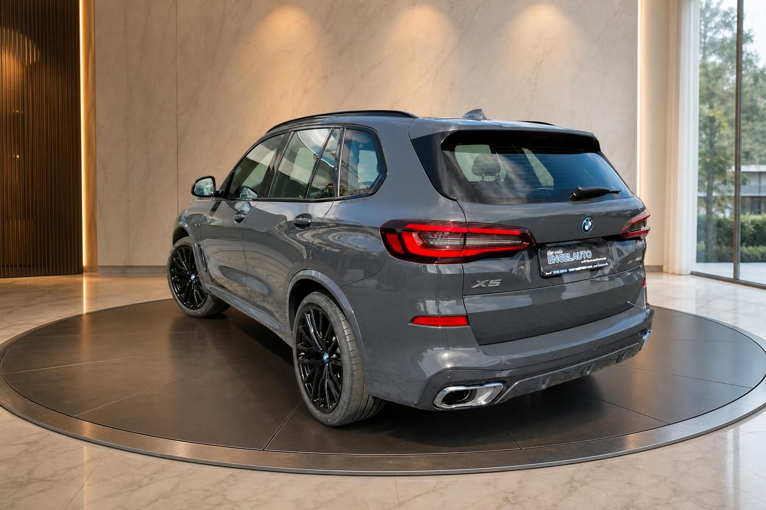 BMW X5 in Grau mit schwarzen Felgen, Heckansicht seitlich im Showroom