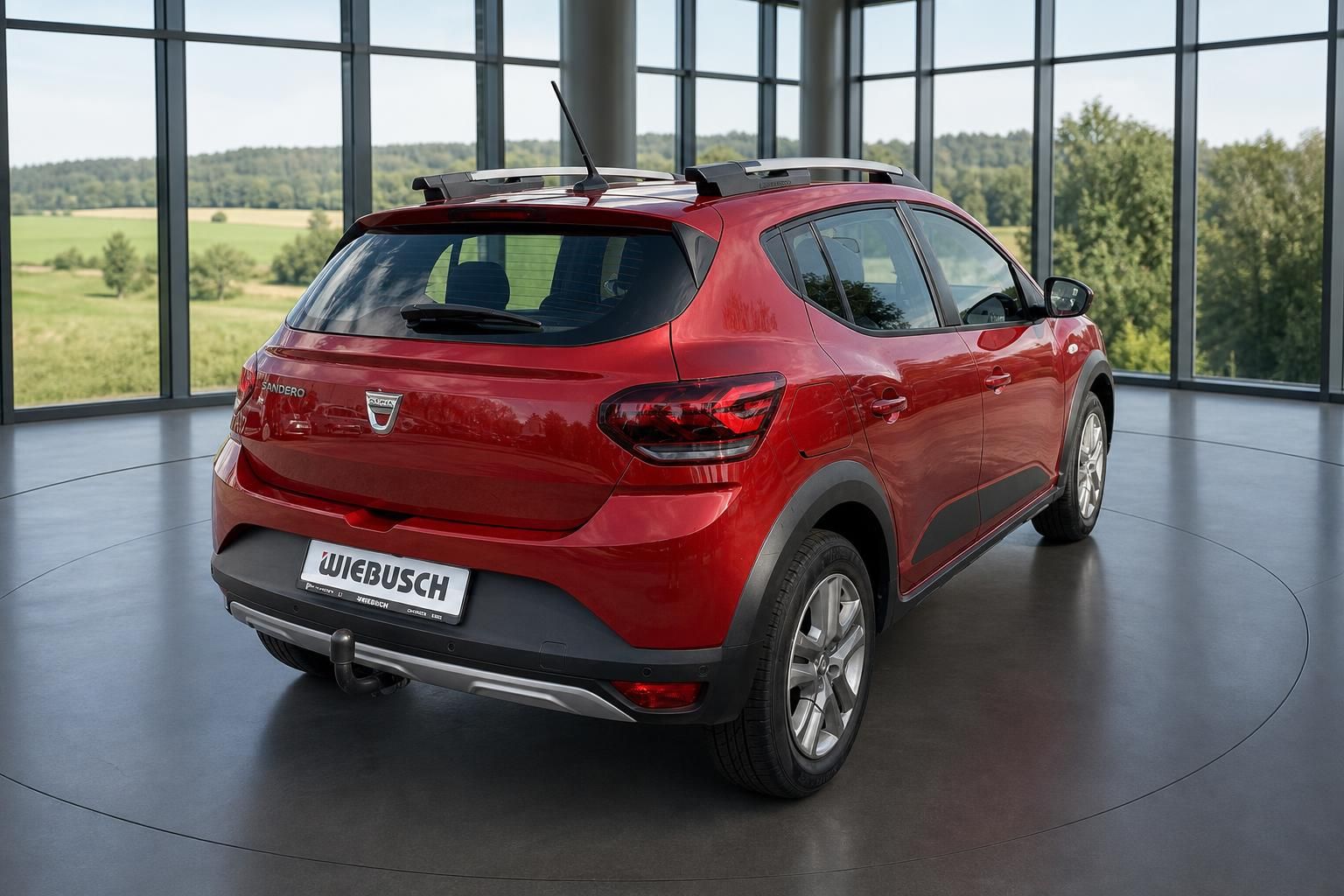 Dacia Sandero rot, Heckansicht im Showroom mit Panoramafenster und ländlicher Aussicht