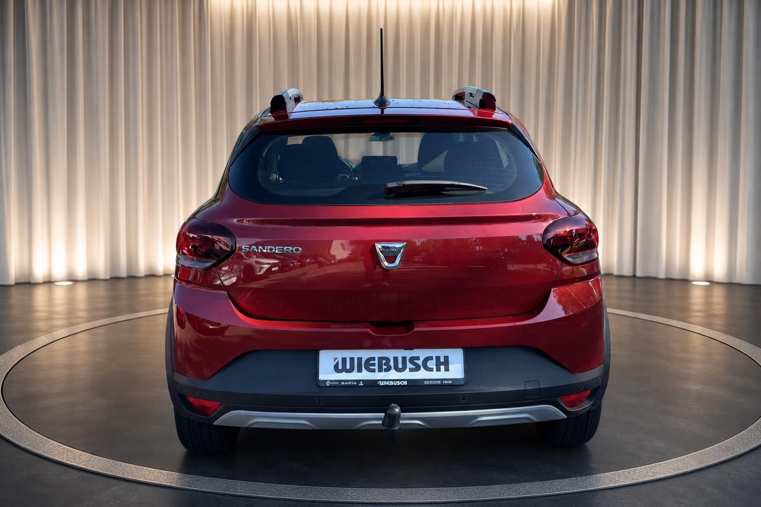 Dacia Sandero in rot, Heckansicht mit Dachträger und WIEBUSCH Kennzeichen im Showroom