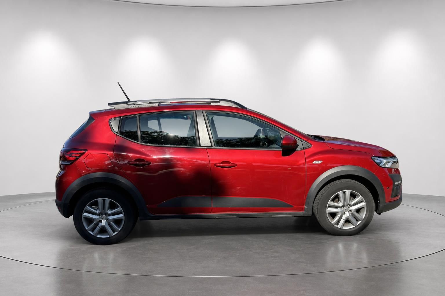 Dacia Sandero in rot, Seitenansicht im Showroom auf Drehteller mit modernem Design