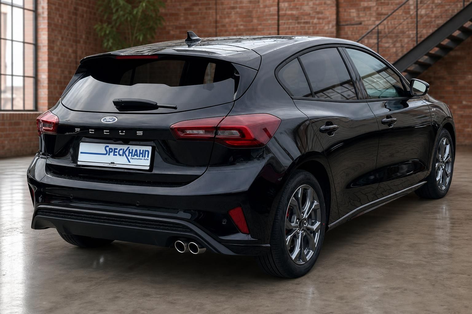 Ford Focus schwarz, Heckansicht schraeg vor Backsteinwand