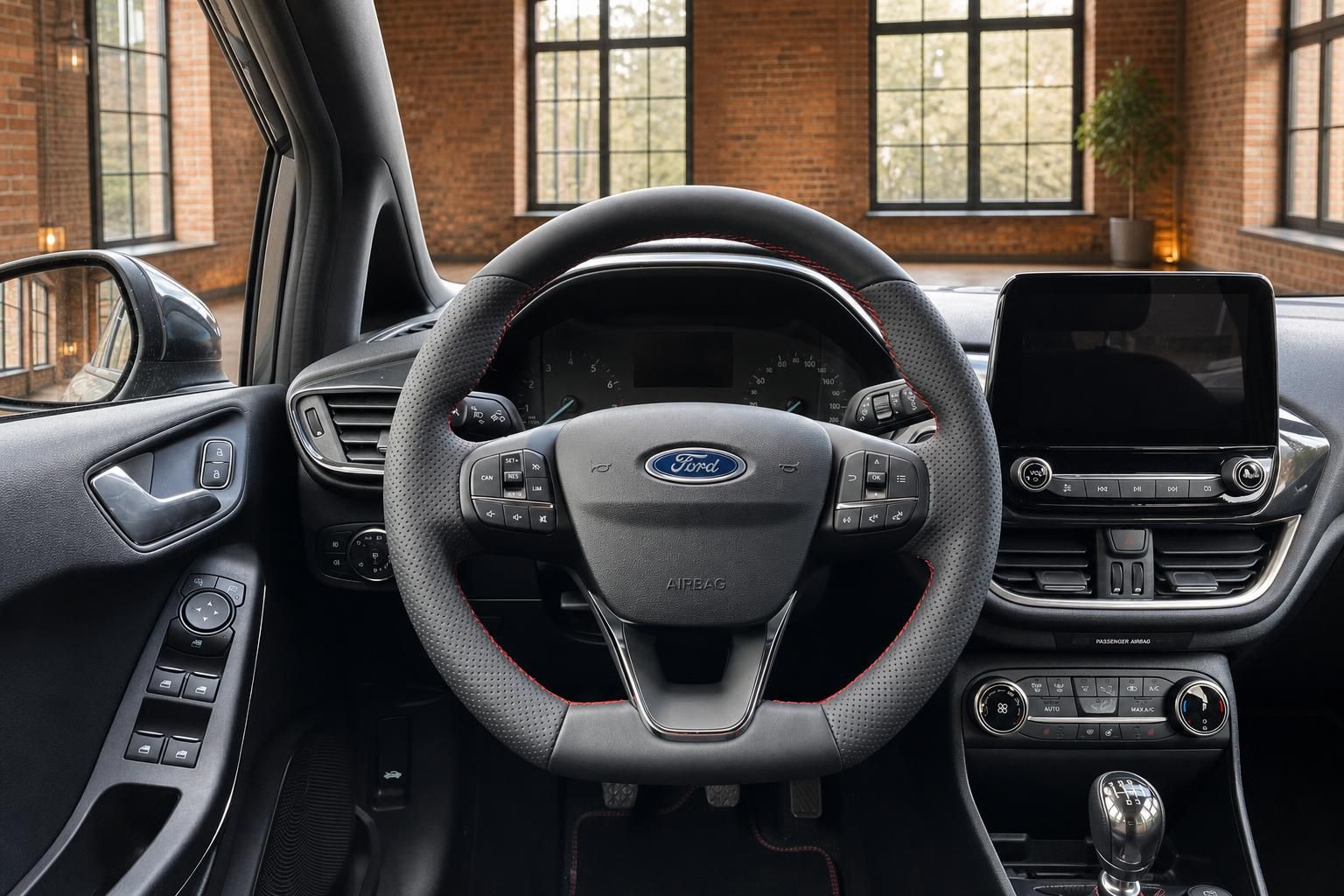Ford Fiesta Lenkrad mit Ford-Logo, Multifunktionstasten, Touchscreen und Klimabedienung im Hintergrund