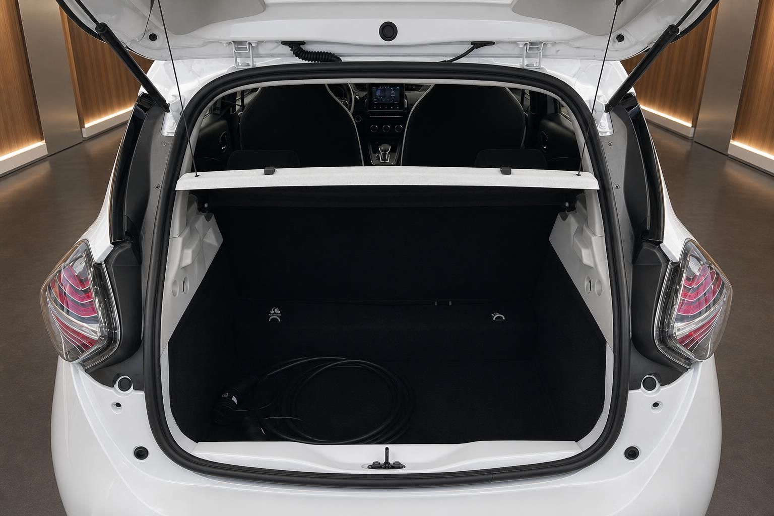 Geöffneter Kofferraum eines weißen Elektroautos mit Ladekabel und schwarzer Innenverkleidung