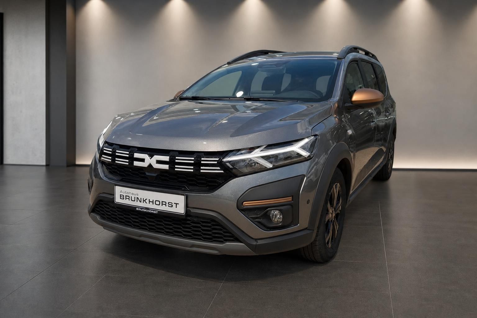 Dacia SUV grau metallic Seitenansicht Scheinwerfer Kühlergrill im modernen Showroom