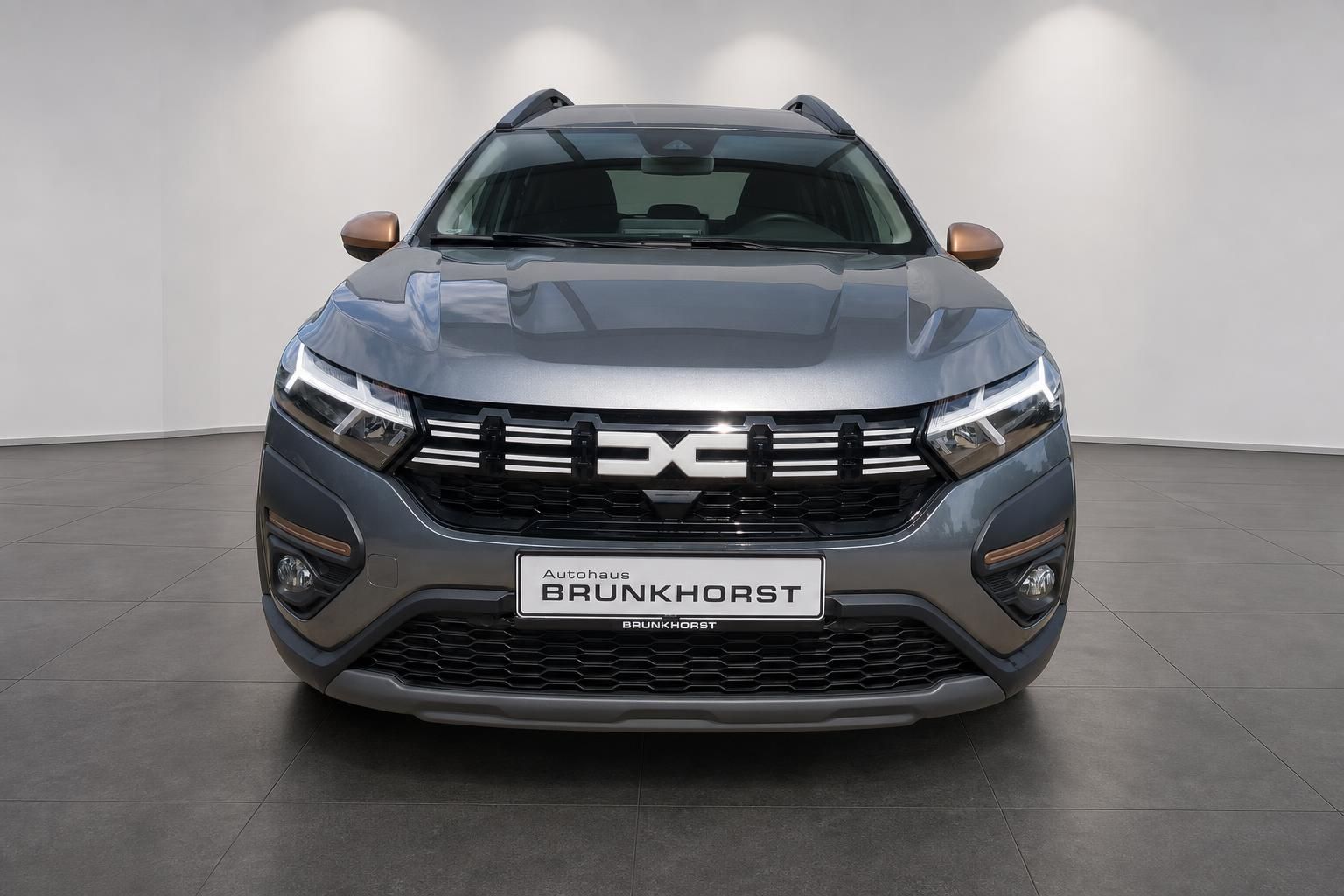 Dacia SUV grau metallic Frontansicht mit Kennzeichen Autohaus Brunkhorst im Showroom