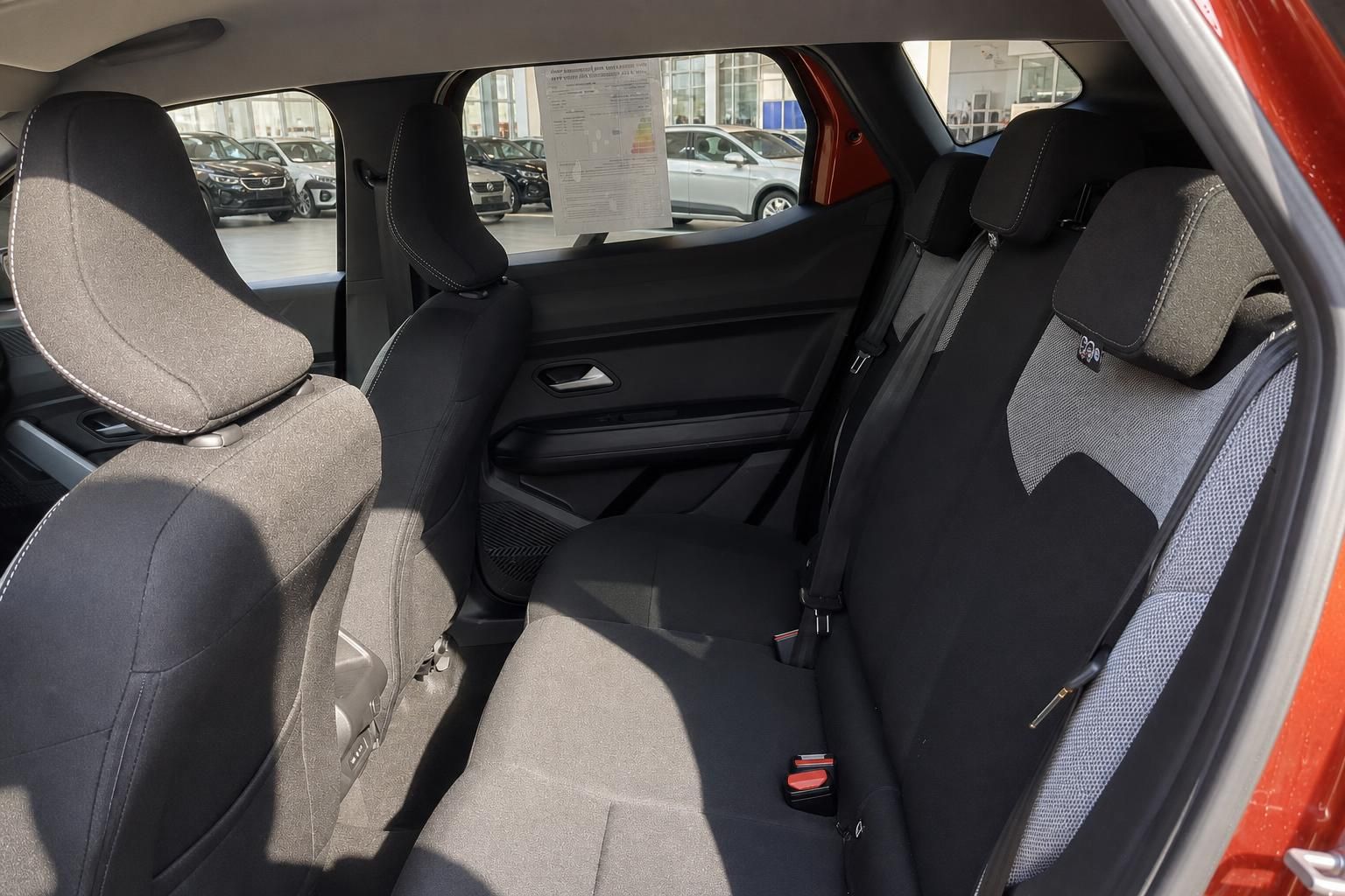Rücksitzbereich des Fahrzeugs mit grauen Polstern und Sicherheitsgurten für Passagiere