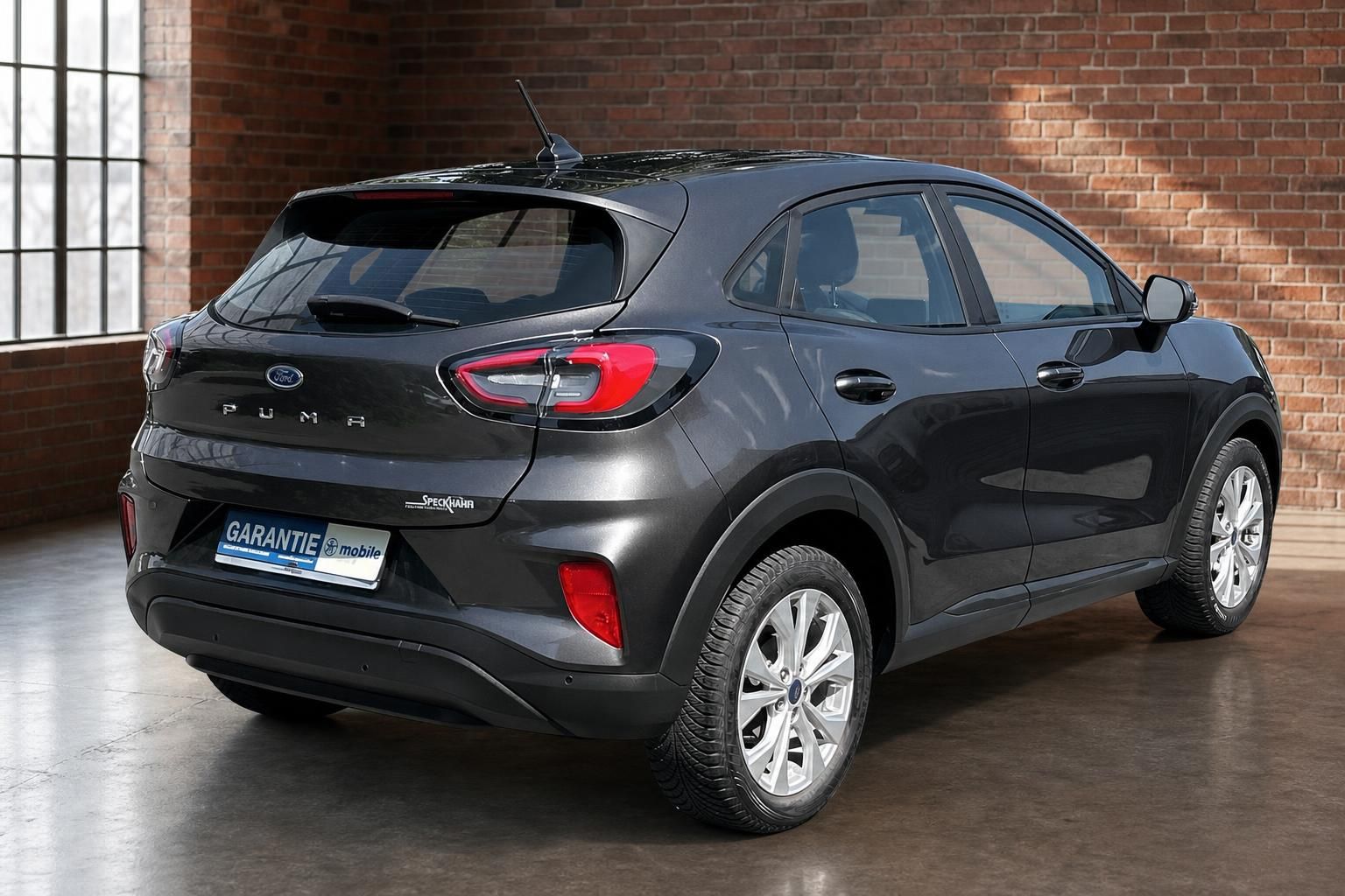 Ford Puma anthrazit Heckansicht schraeg vor Ziegelwand