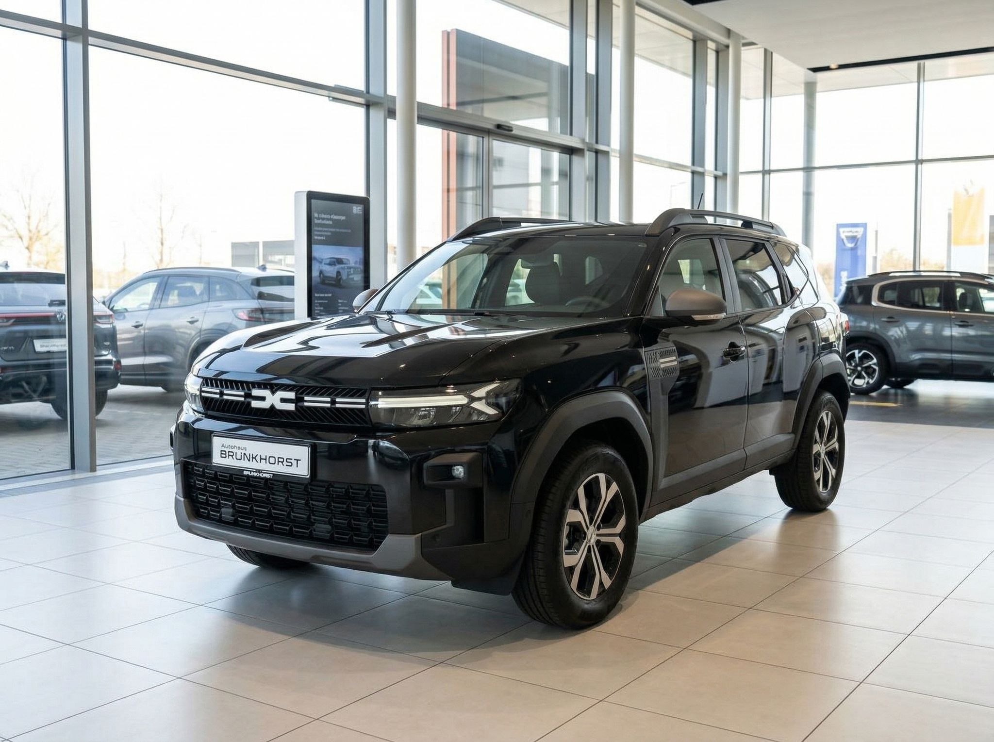 Schwarzer Dacia Bigster SUV in modernem Autohaus-Showroom von vorne seitlich fotografiert