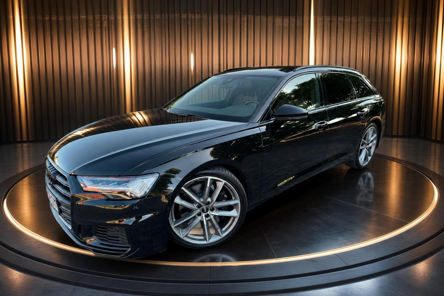 Schwarzer Audi A6 Avant Kombi Schrägansicht vorne auf beleuchteter Drehbühne im Showroom