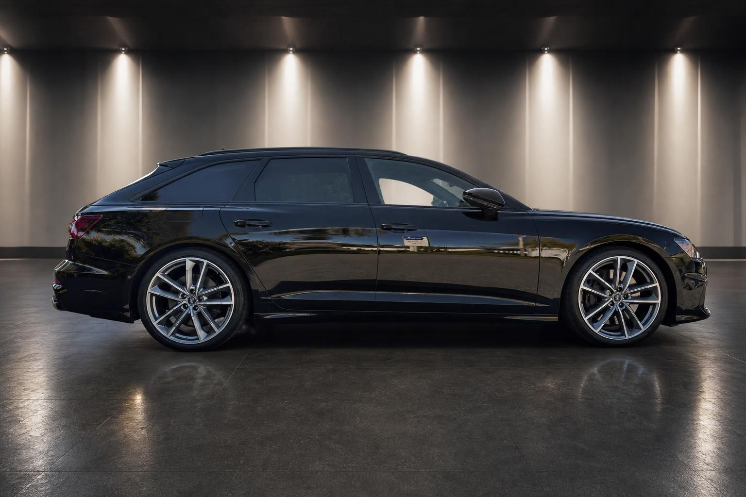 Schwarzer Audi A6 Avant Seitenansicht mit Sportfelgen in elegantem Ausstellungsraum
