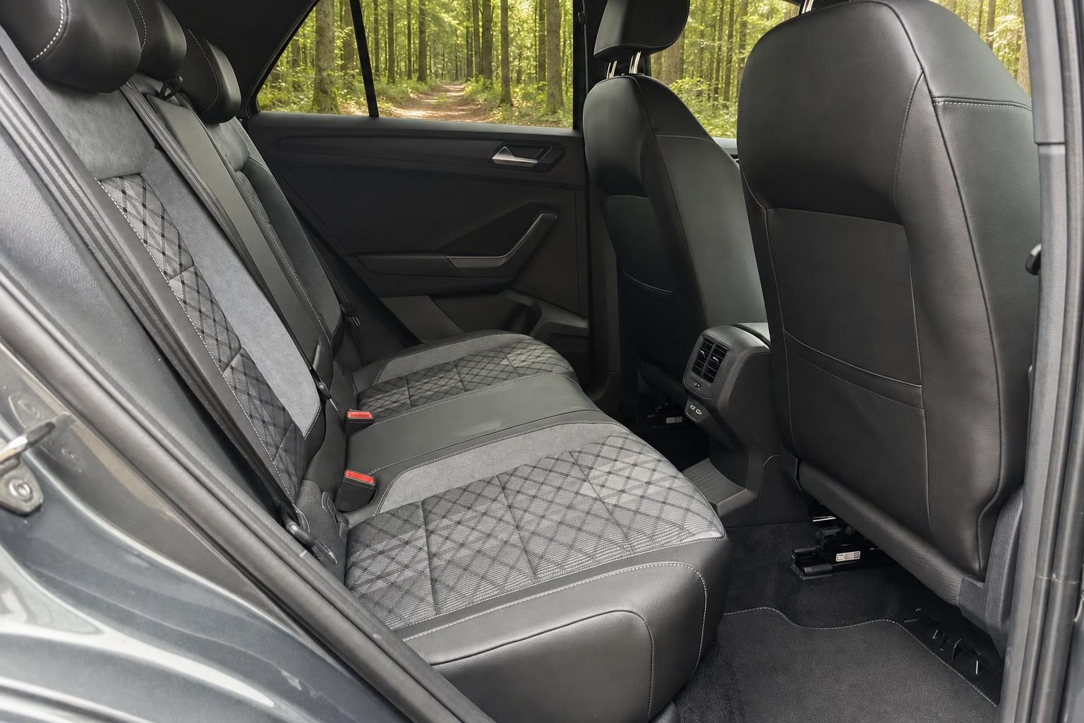 Rückbank des Volkswagen T-Roc mit grauen Ledersitzen und Rautensteppung in Waldumgebung