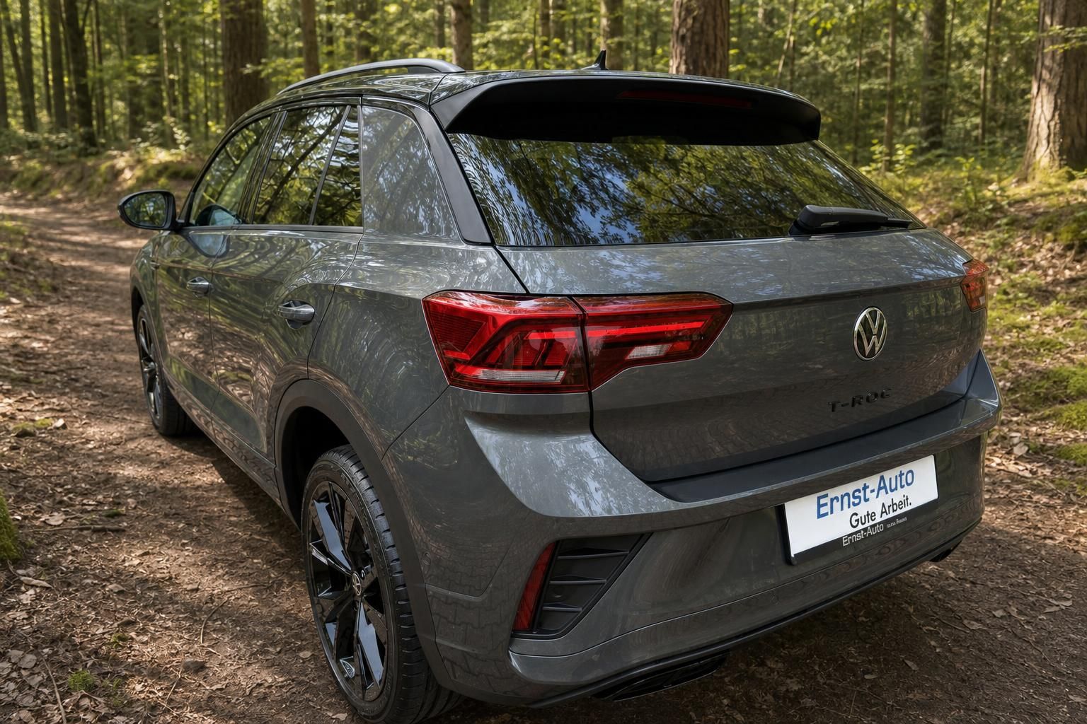 Volkswagen T-Roc Heckansicht in grauer Metallic-Lackierung mit LED-Rückleuchten im Wald