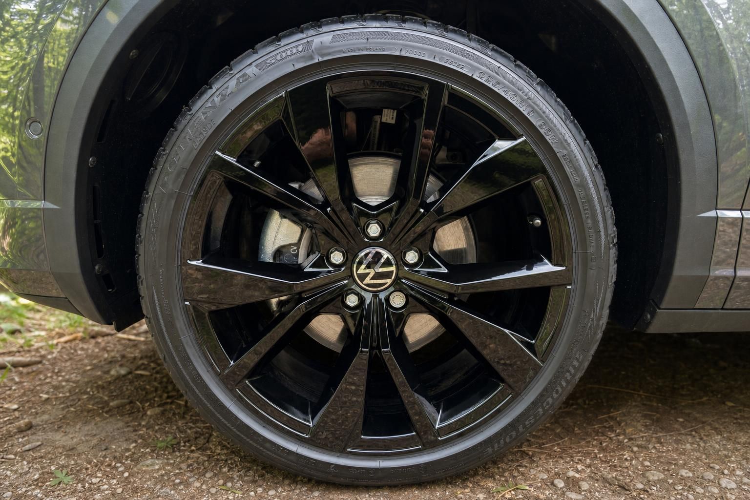 Schwarze Leichtmetallfelge des Volkswagen T-Roc mit VW-Logo und Sportreifen Detailaufnahme