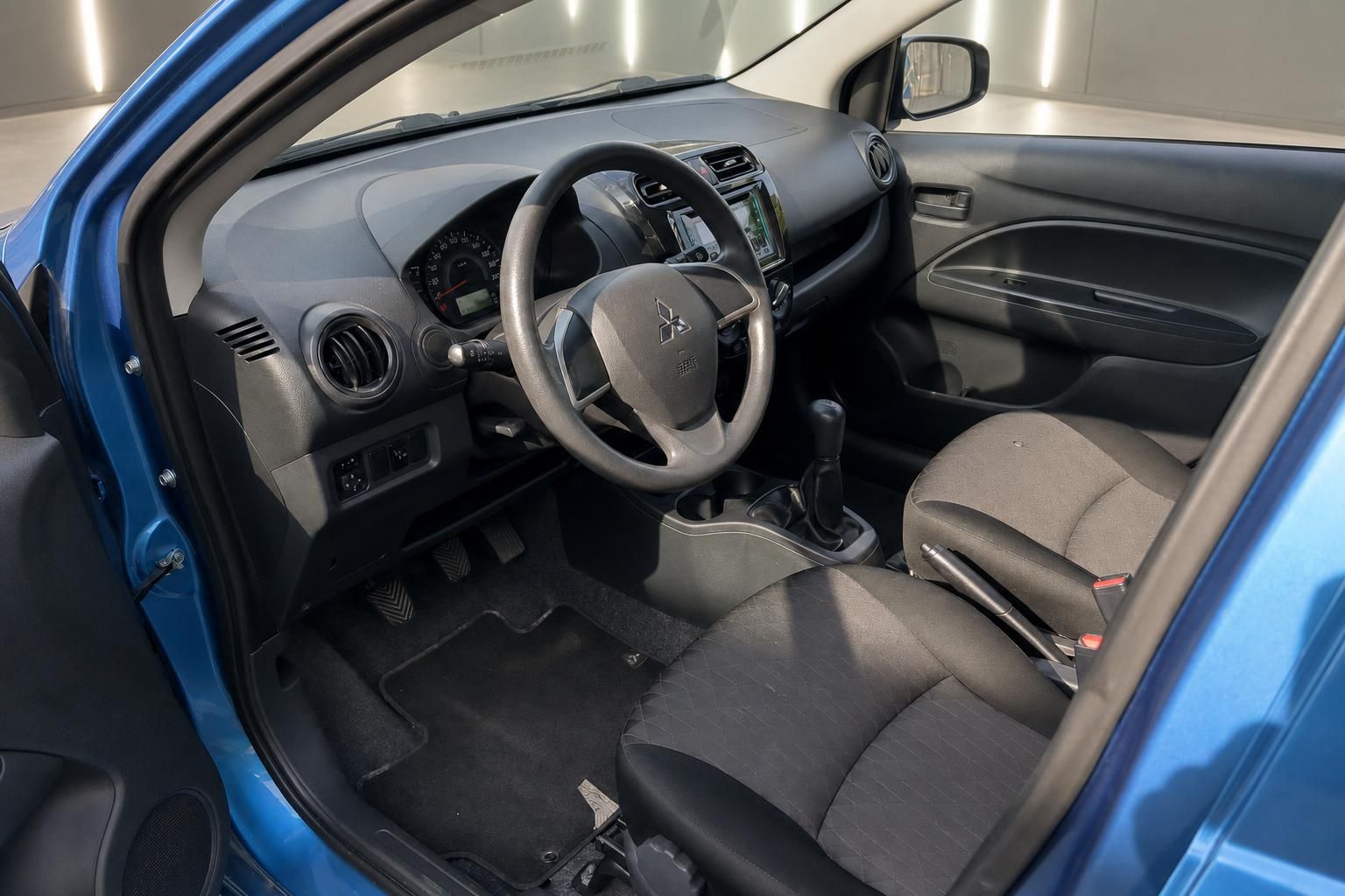 Mitsubishi Innenraum mit schwarzem Lenkrad, Armaturenbrett und grauem Fahrersitz