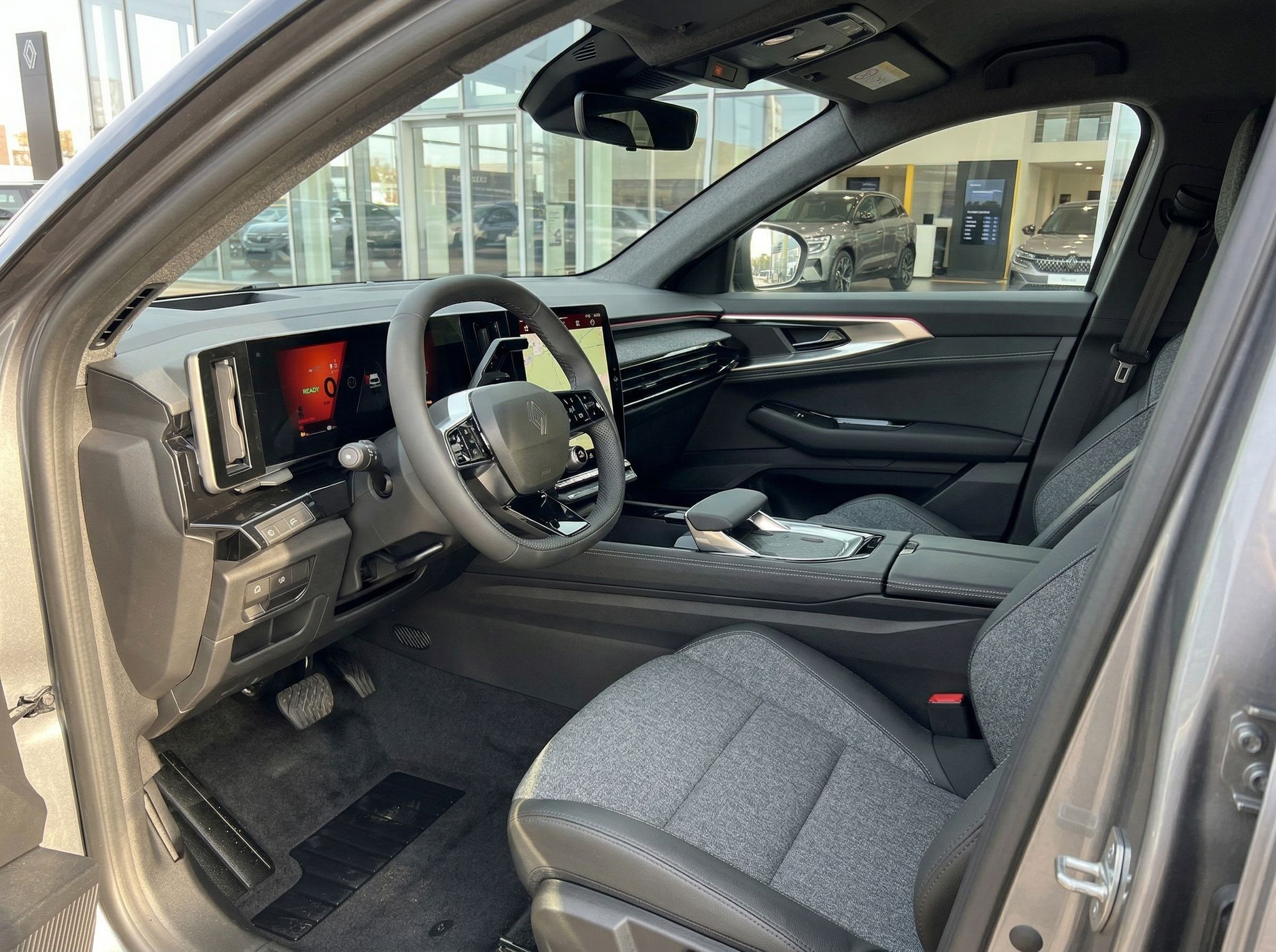 Fahrzeuginnenraum mit schwarzem Cockpit, Lenkrad und modernem Display