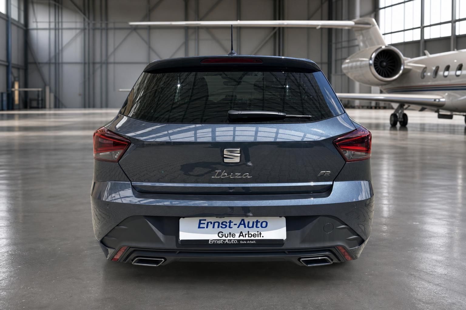 SEAT Ibiza grau metallic Heckansicht in Fahrzeughalle mit Kennzeichen und Auspuff