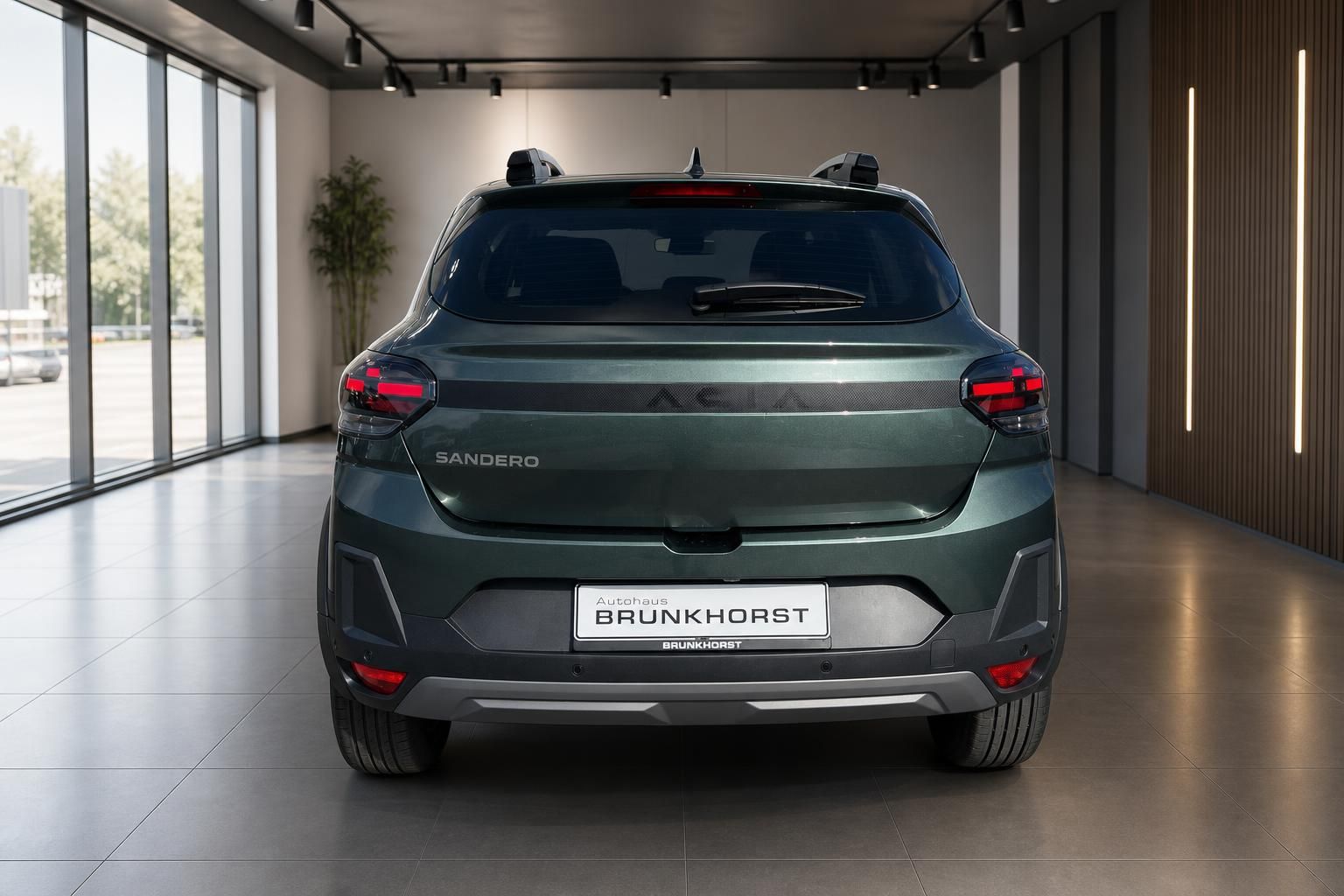 Dacia Sandero Heckansicht in grüner Metallic-Lackierung im modernen Autohaus Showroom