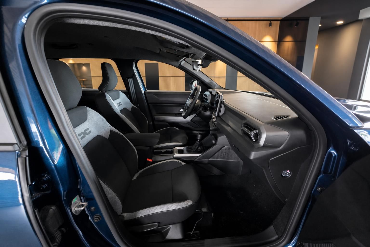 Blick in den Innenraum eines blauen Dacia mit offener Fahrertür